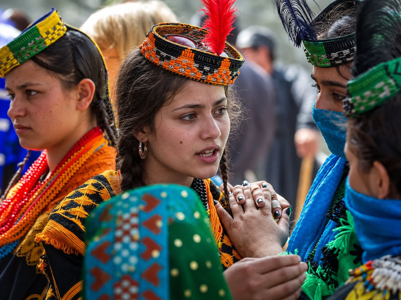 Kalasha women gathered closely together, one holding a length of blue patterned cloth