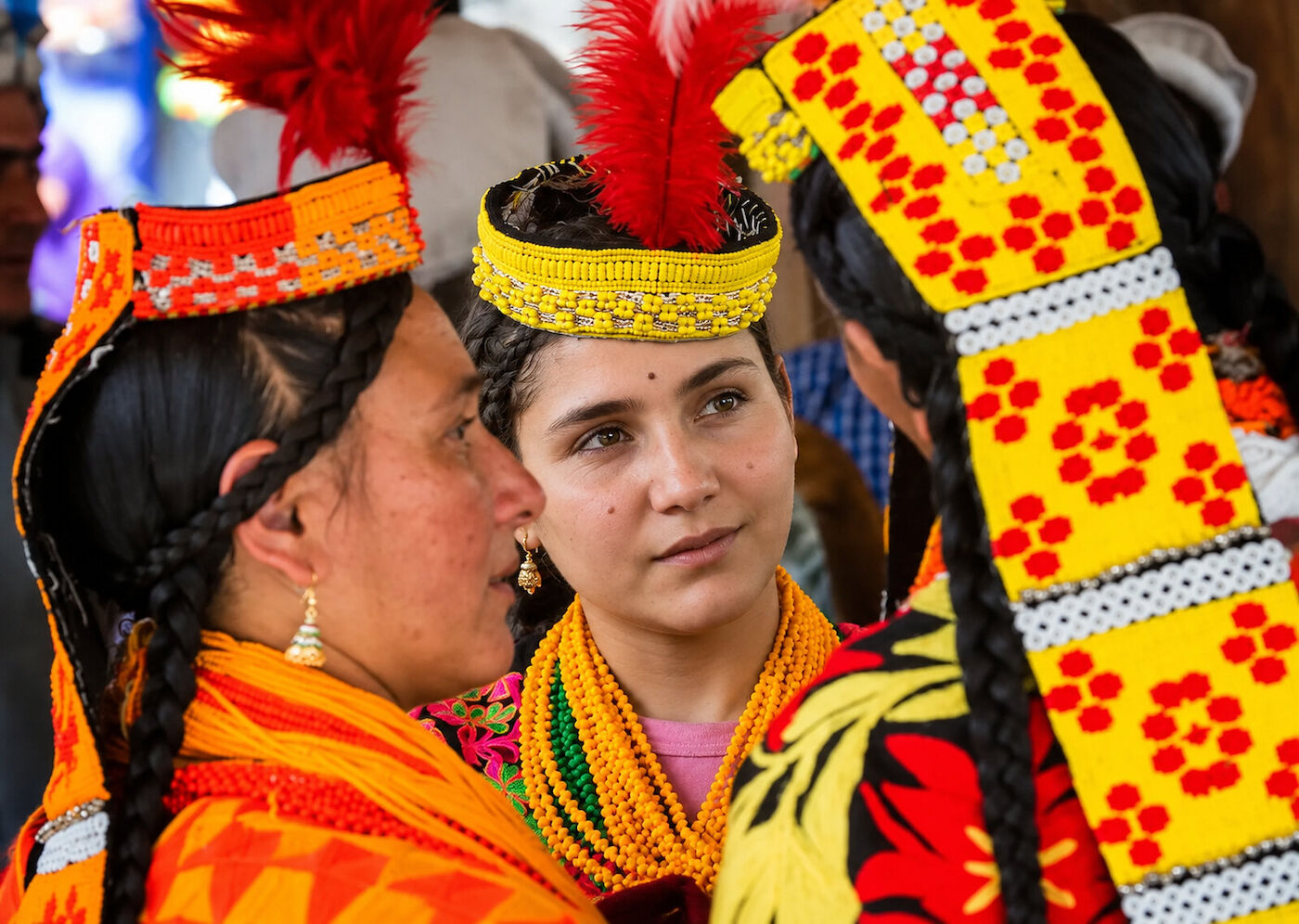 Close view of two Kalasha women in yellow and red patterned headdresses